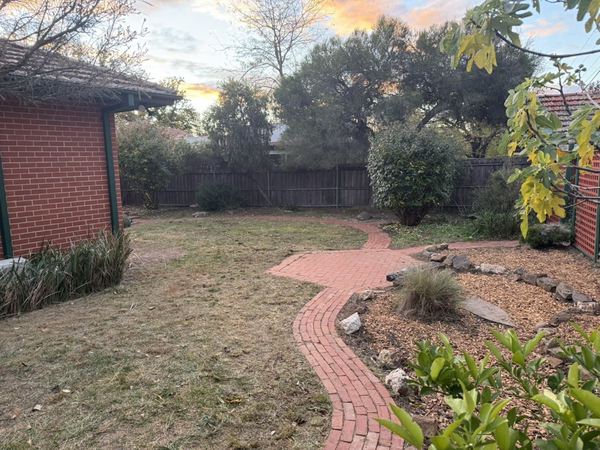 Brick path curving through a tidy garden